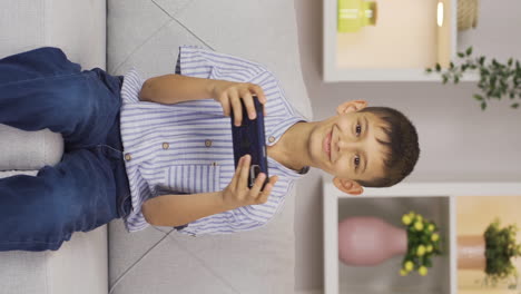 Vertical-video-of-Phone-addicted-boy-plays-games-on-the-phone-at-home
